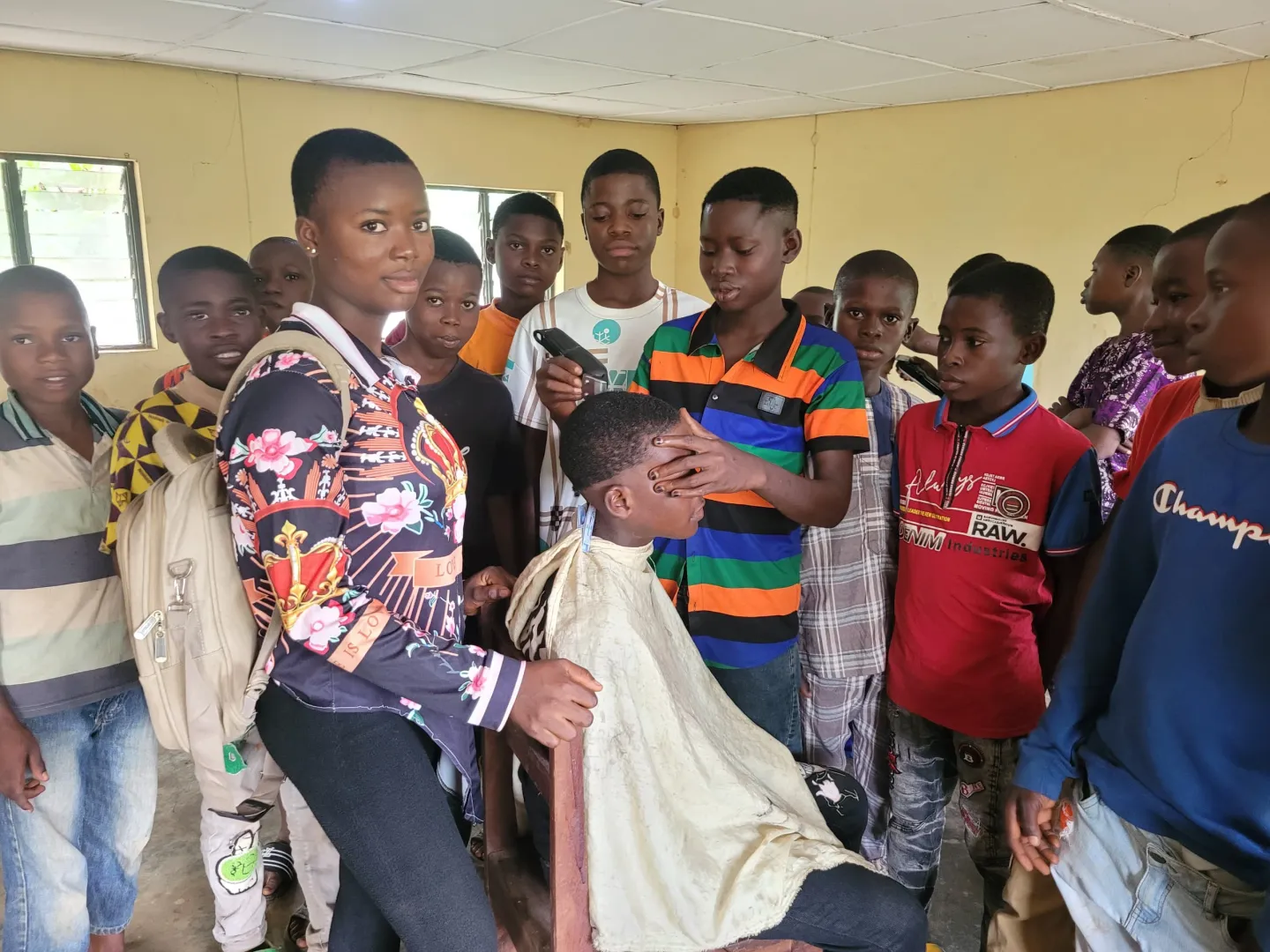 A student cuts a volunteers hair, while other students look