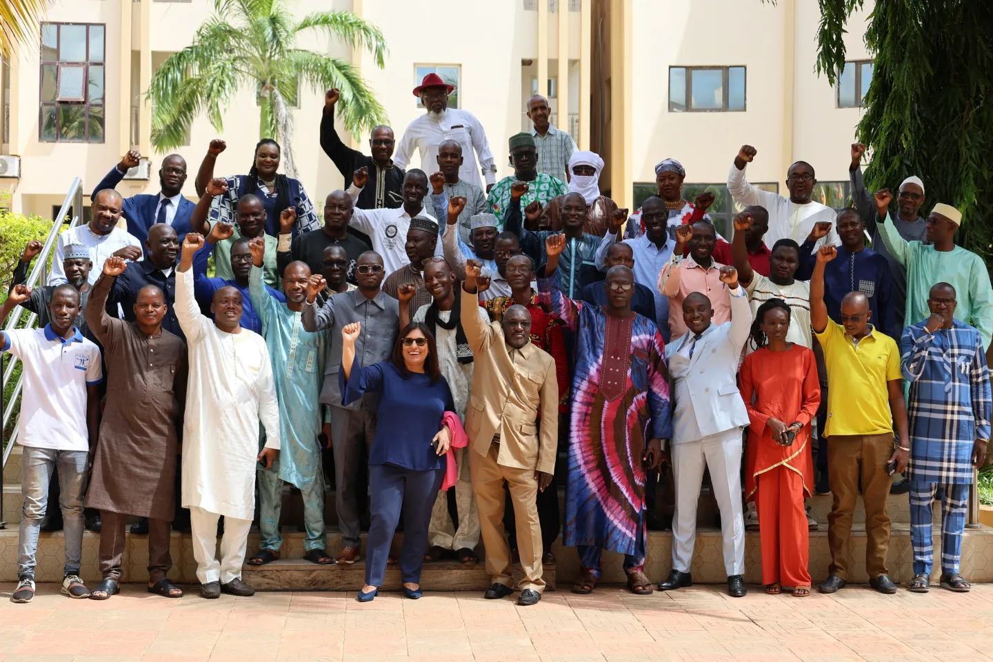 Participants to a meeting pose for a picture raising their hand as a sign of unity