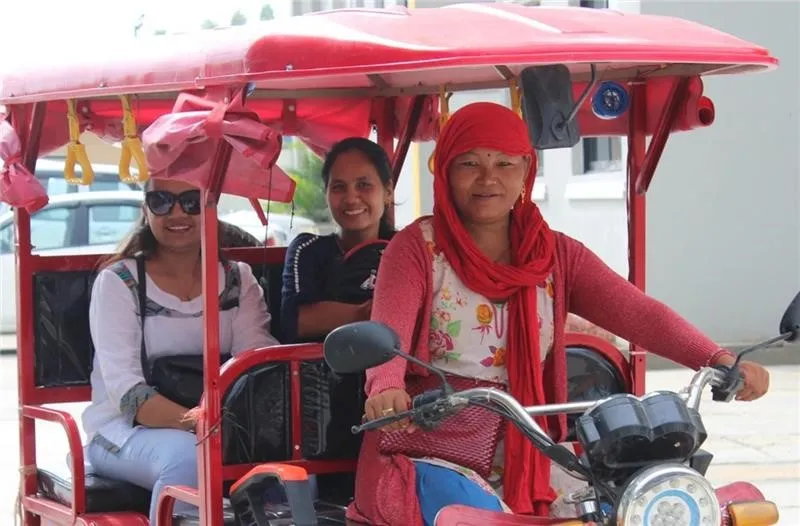 A woman driving an electronic rickshaw, striving for economic independence.