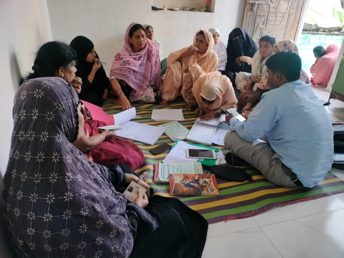Women and a man sitting together in a community meeting