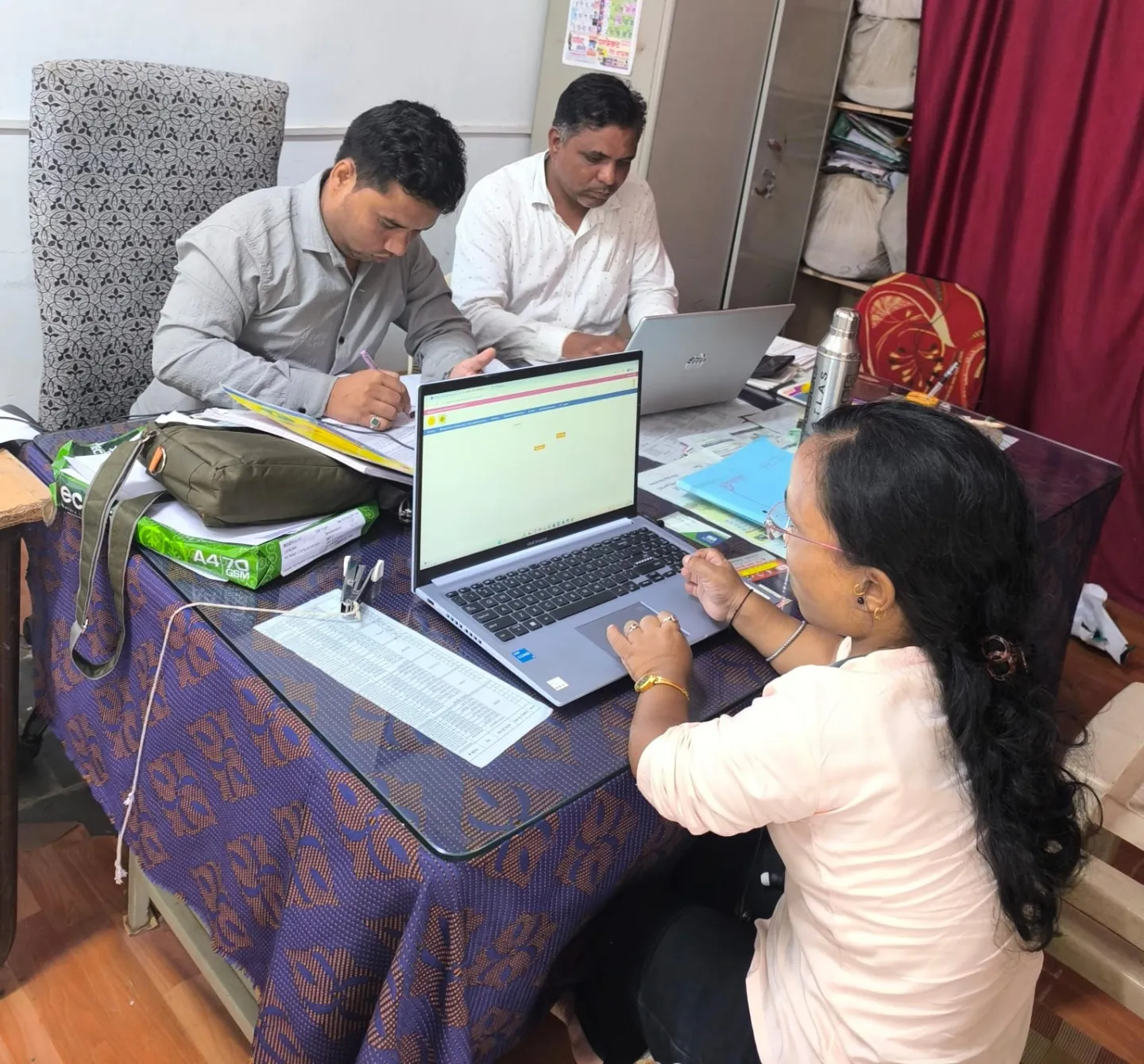 Three people sitting in an office with their laptops 