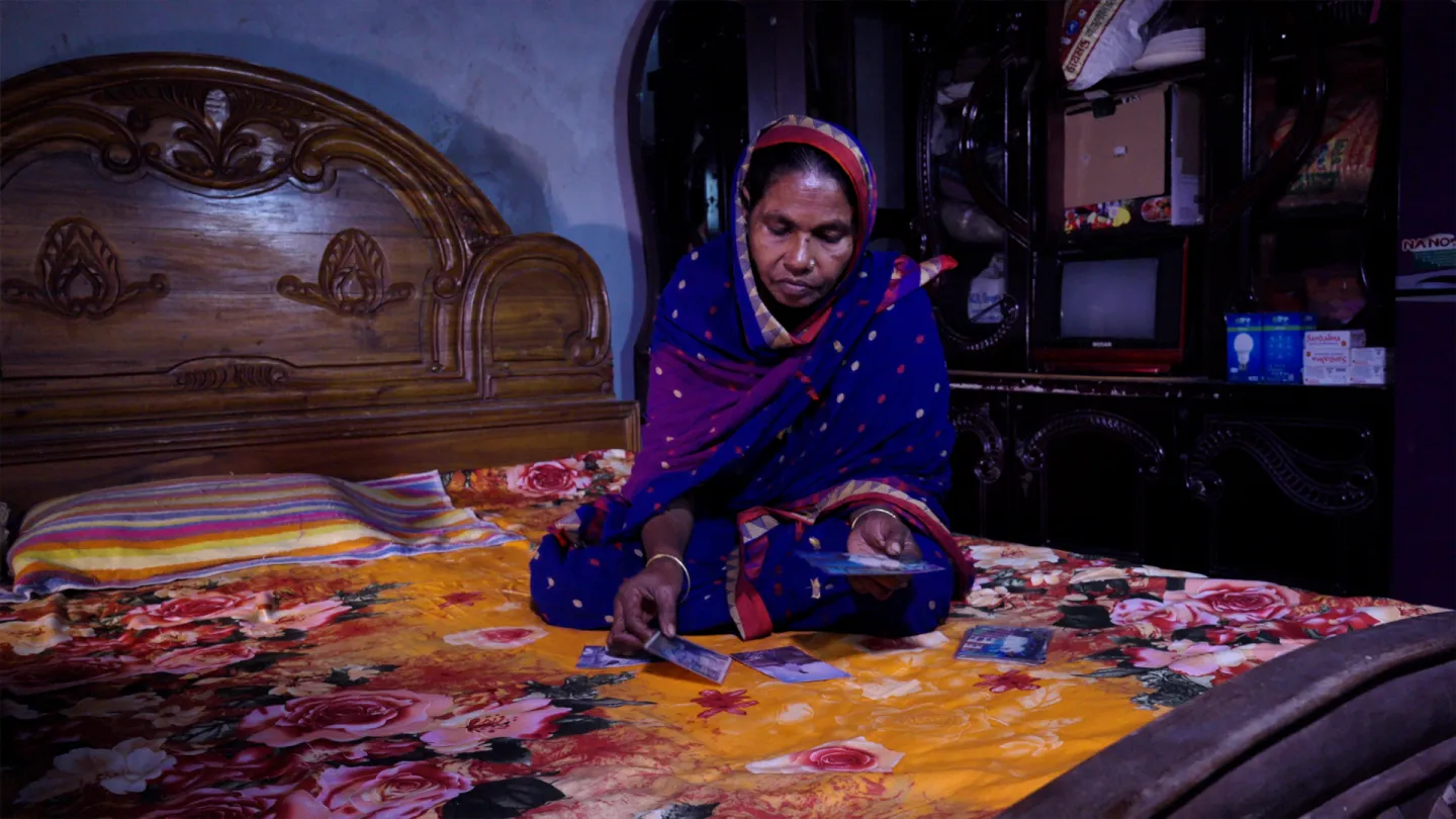 Juleka, in her bedroom, looks through photos of her deceased son, Nuzrul 