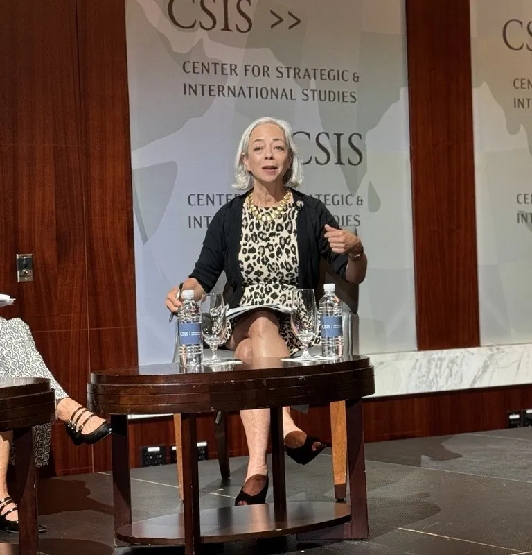 Older woman sitting and speaking with hand raised