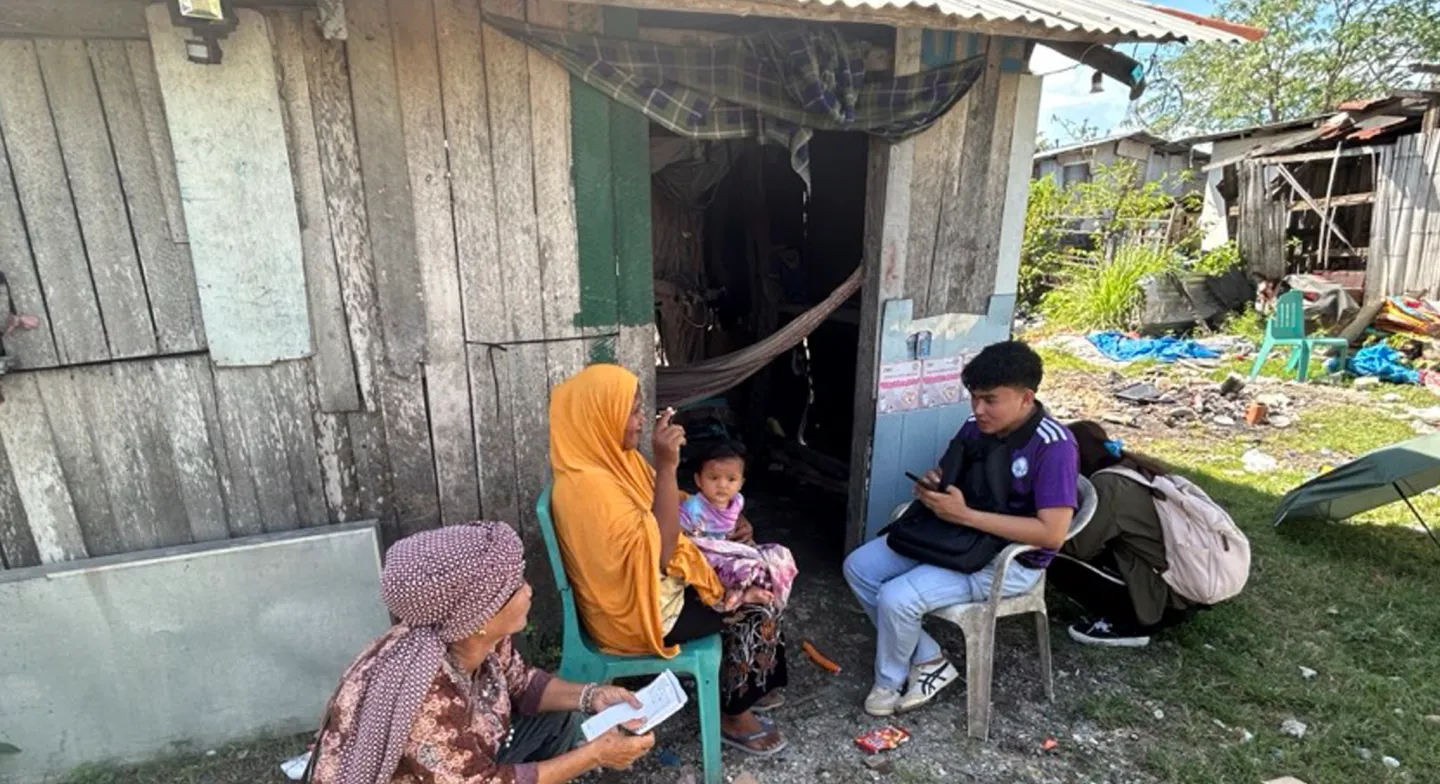 a man holds his mobile phone and interviews two women