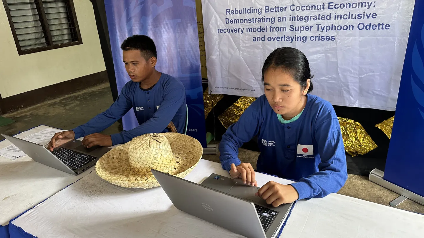 male and female workers use a laptop to register online for social protection