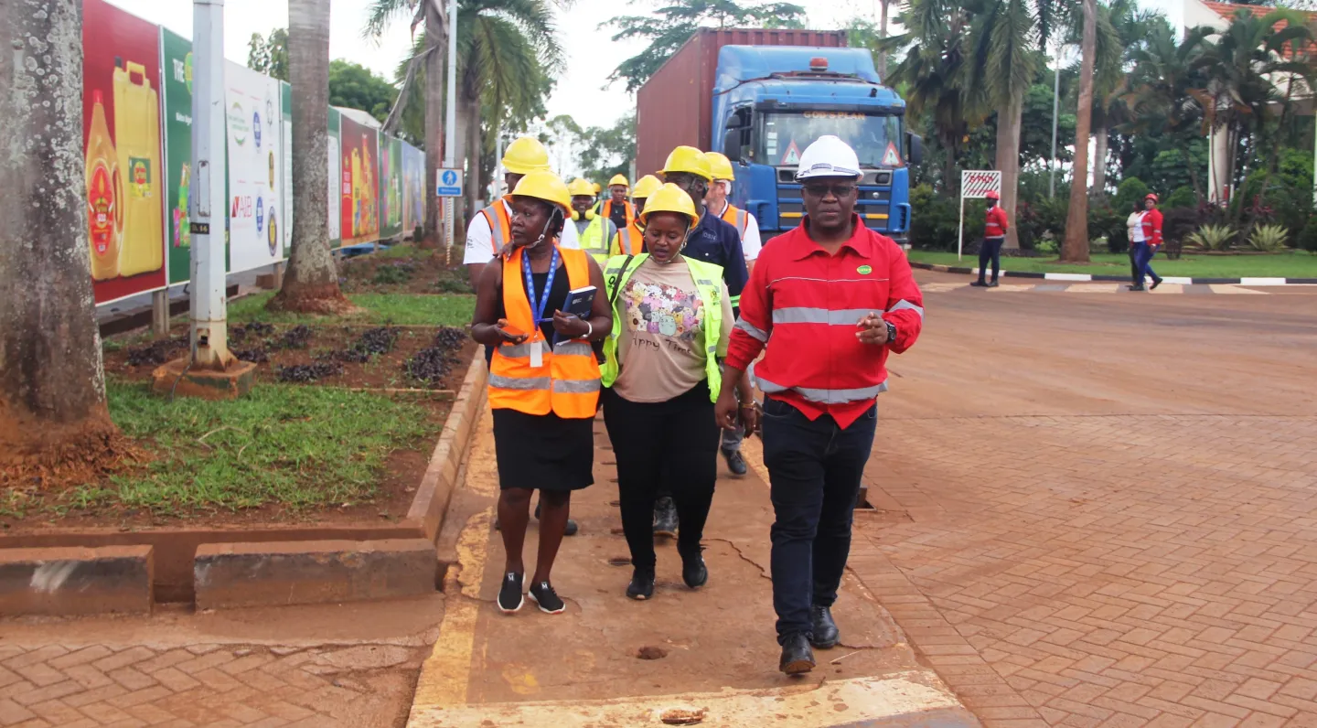 Participants walk with protective equipment towards a tea factory