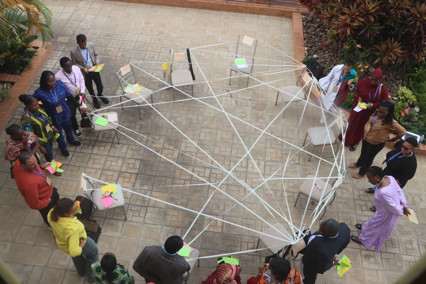 Participants stand in circle around some chairs that are linked to each other representing challenges in the labour market