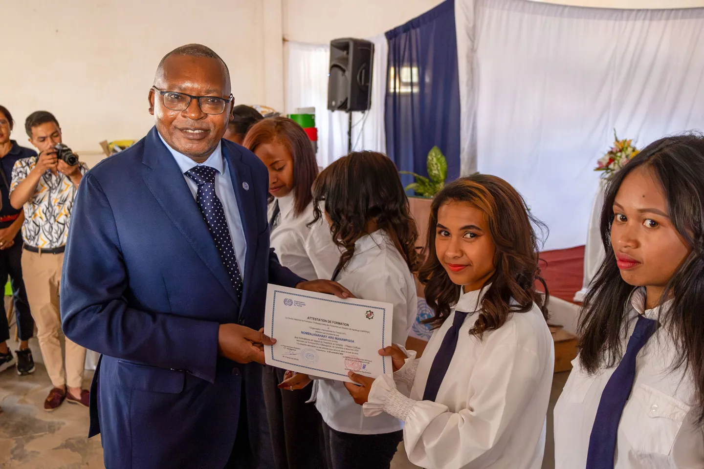 Une jeune femme diplômée brandit son diplôme à côté de Frederick Muia, Directeur du Bureau de pays de l'OIT pour Madagascar, Comores, Maurice et Seychelles.