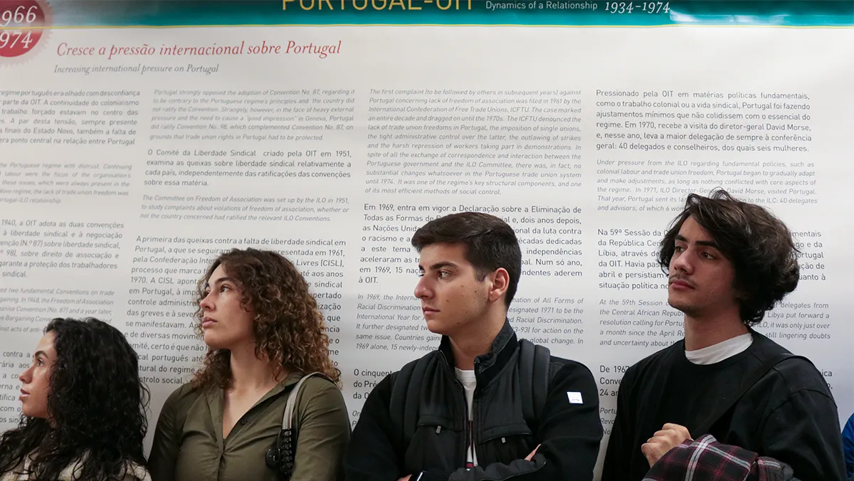 Grupo de jovens em frente a painel da Exposição "Diálogos na história de Portugal na OIT. A consolidação da democracia laboral"