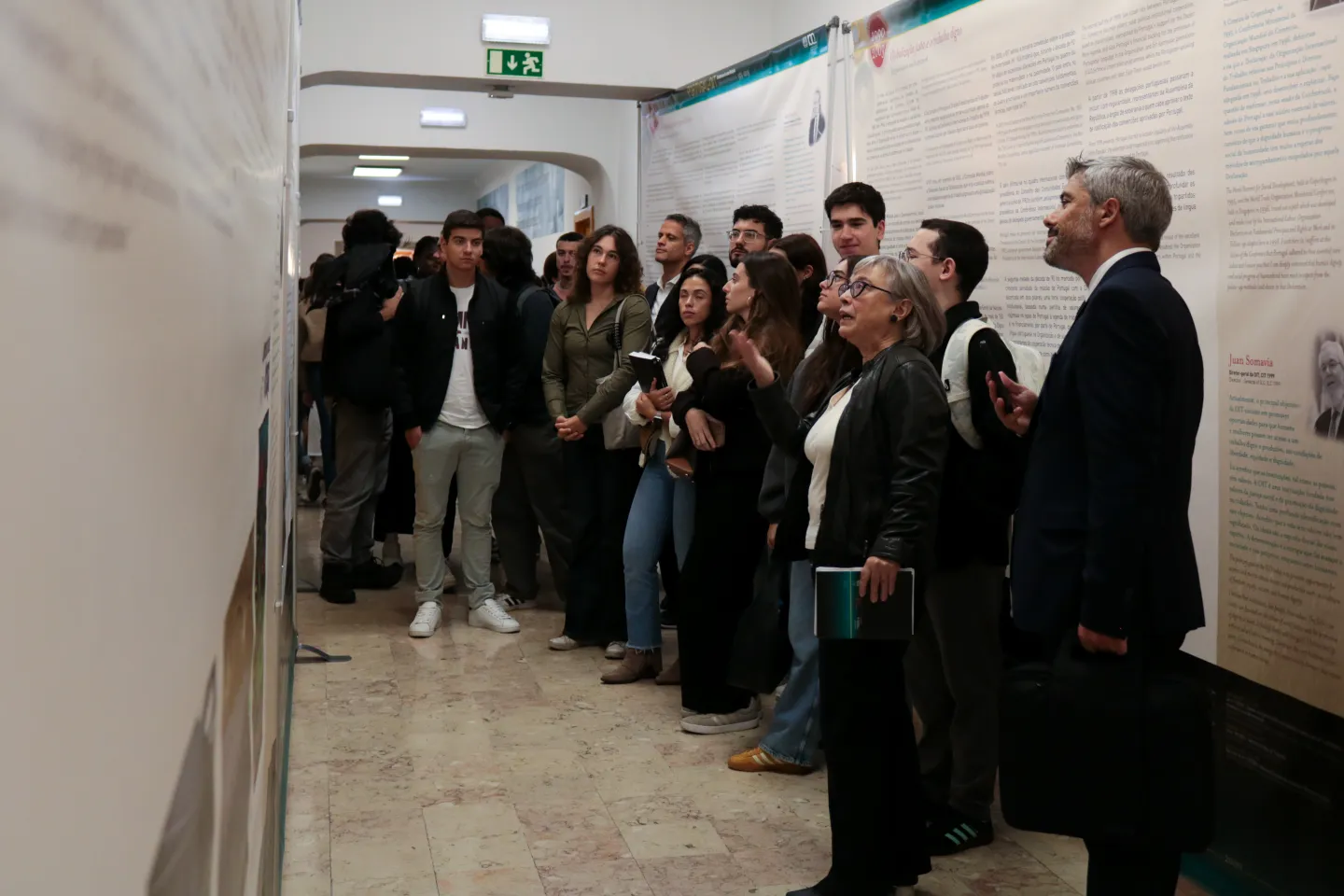Grupo de alunos olham os painéis durante a visita guiada à exposição