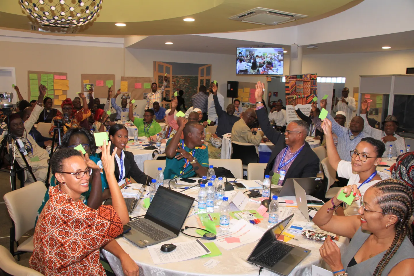 Les participants au Forum sur l'informalité à Abidjan s'assoient autour d'une table et lèvent la main pour voter.