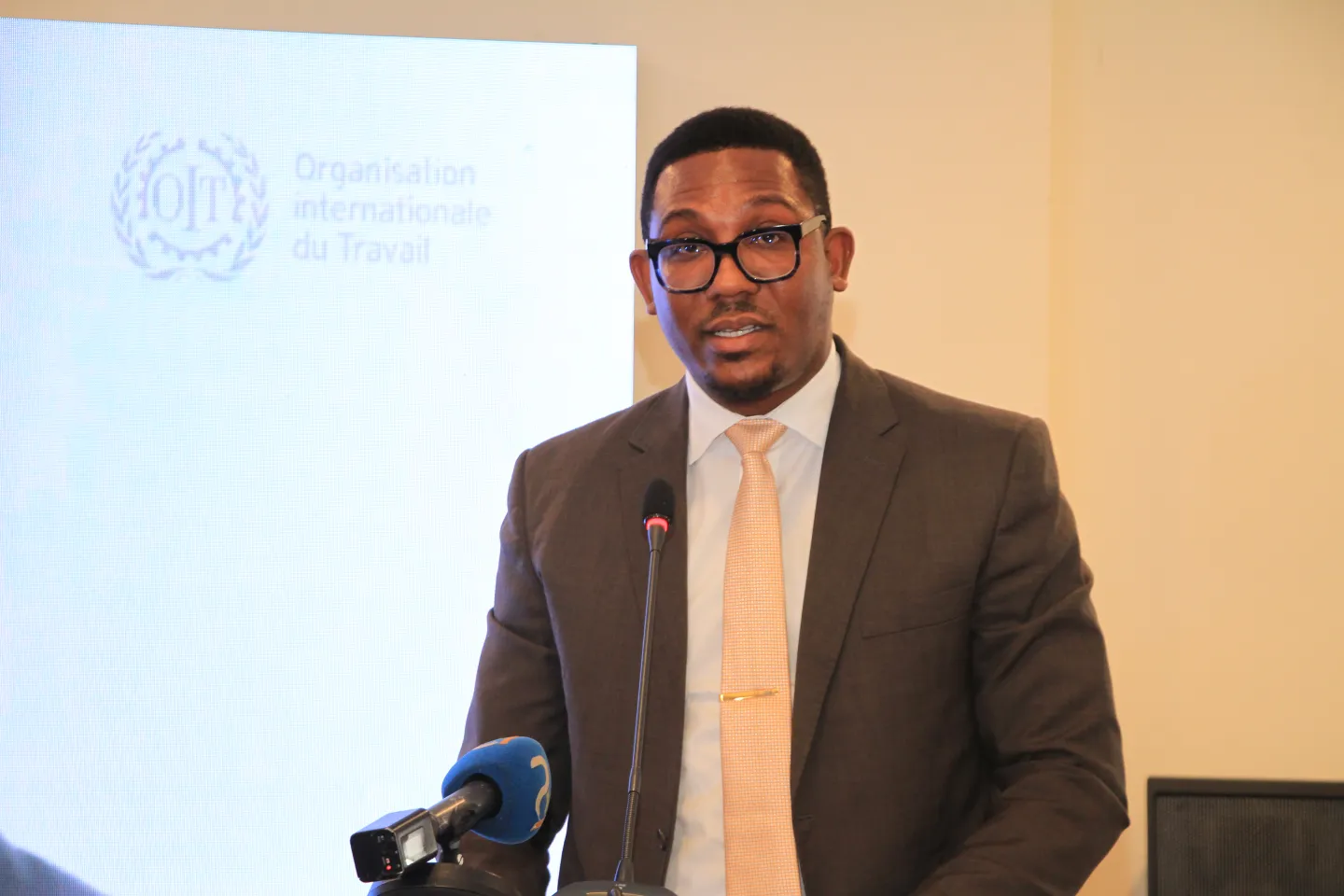 Aubin Gnoléba Tapé, directeur de cabinet du ministre ivoirien de l'emploi et de la protection sociale, se tient derrière un podium pour prononcer son discours d'ouverture du Forum sur l'informalité.