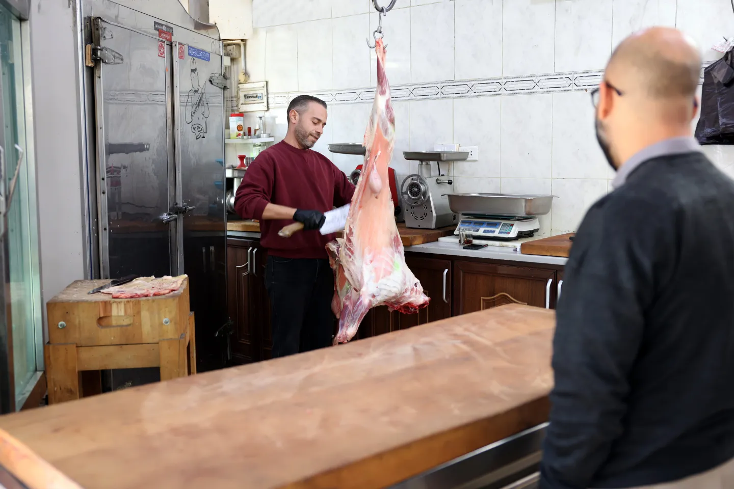 Eyad serves a customer at the butcher shop where he works.