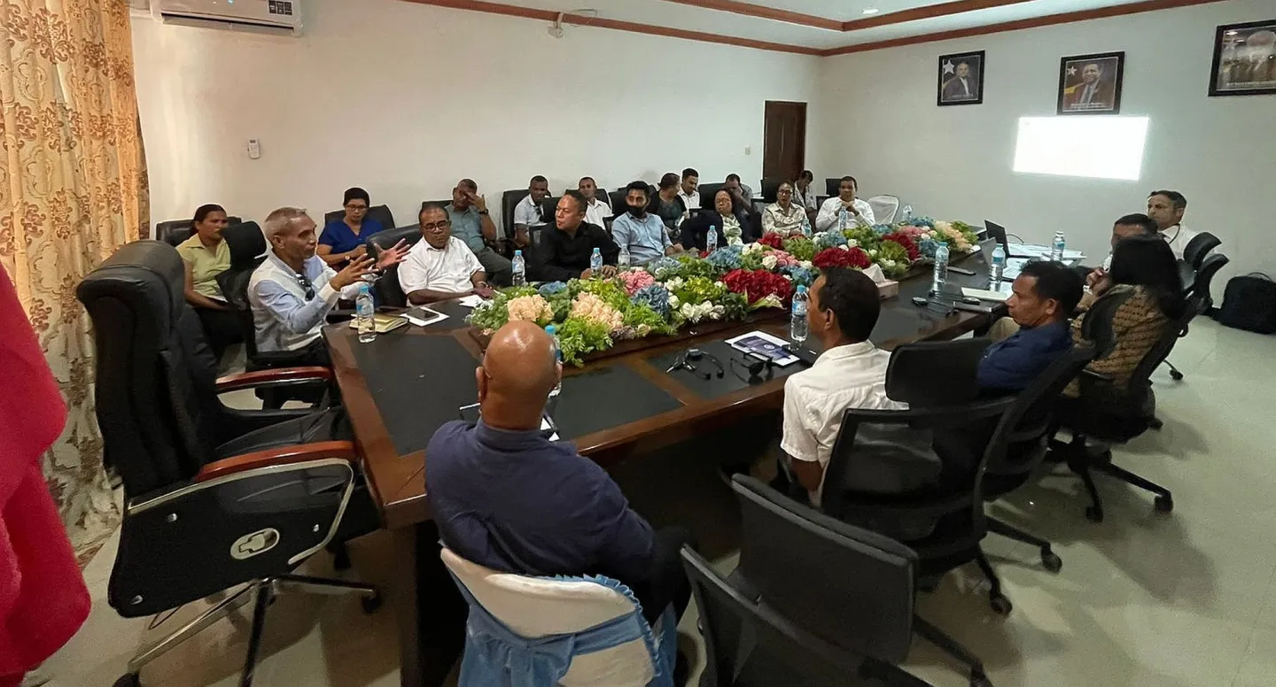 A group of people sitting surrounded a long meeting table.