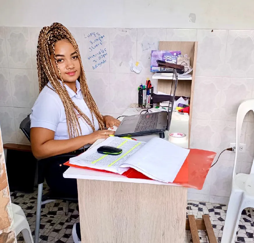 Mujer afro sonriente sentada frente a un escritorio con un computador.