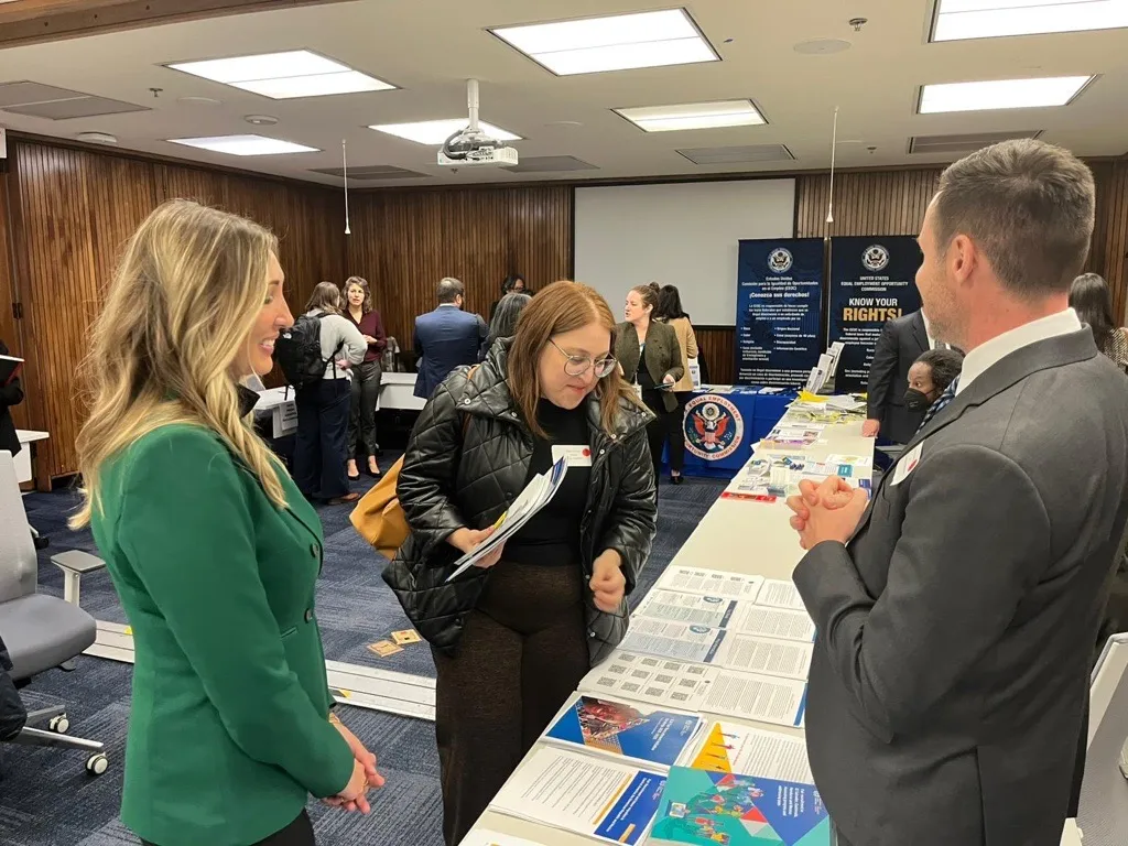 two women and a man standing in fron t of a table with publications