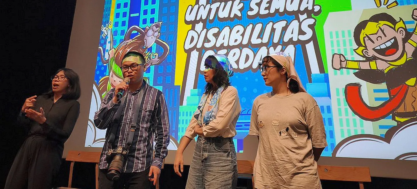 Four people standing in front of an event banner, three women and one man.