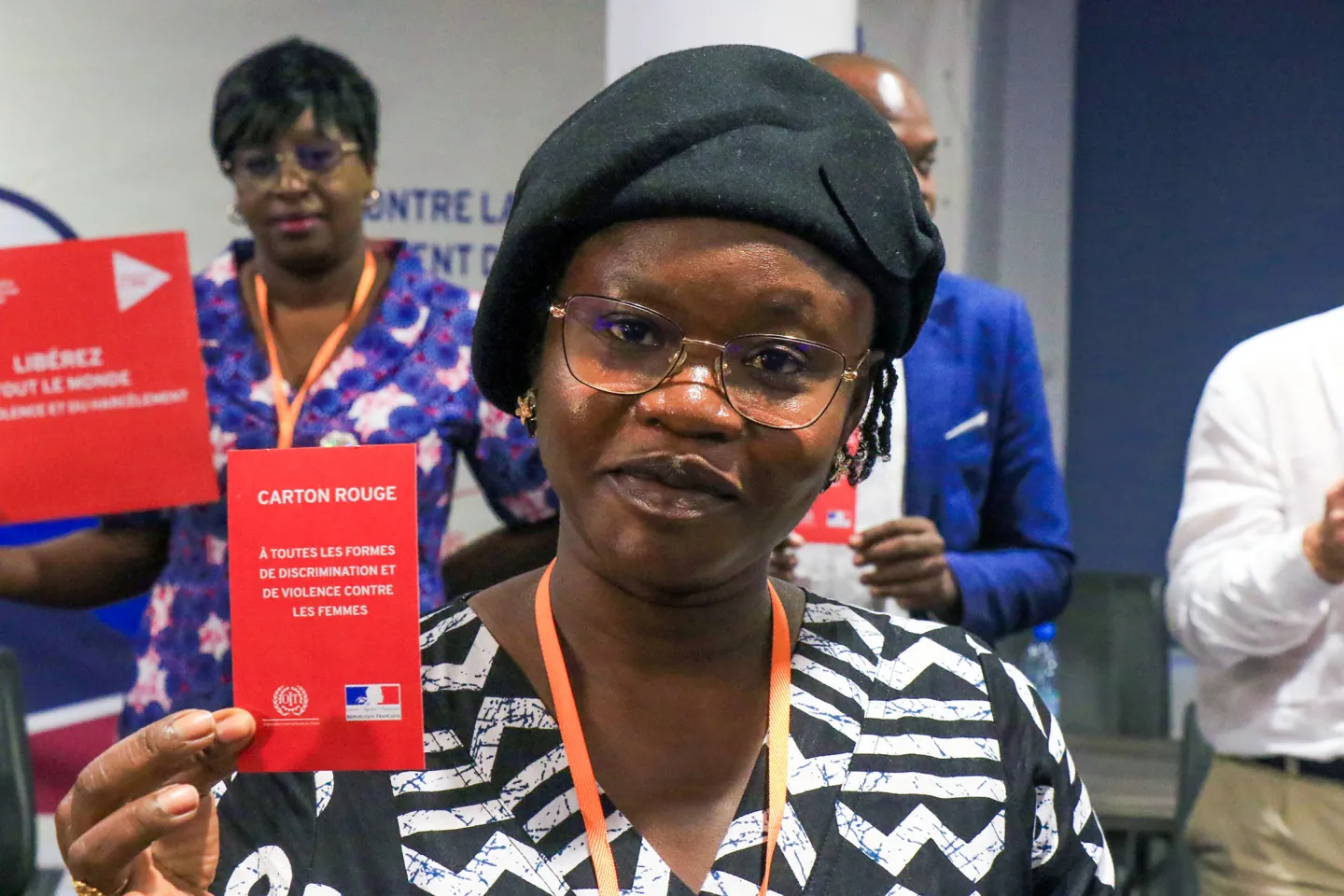 Portrait d'une participante tenant un carton rouge contre la violence et du harcèlement dans le monde du travail.