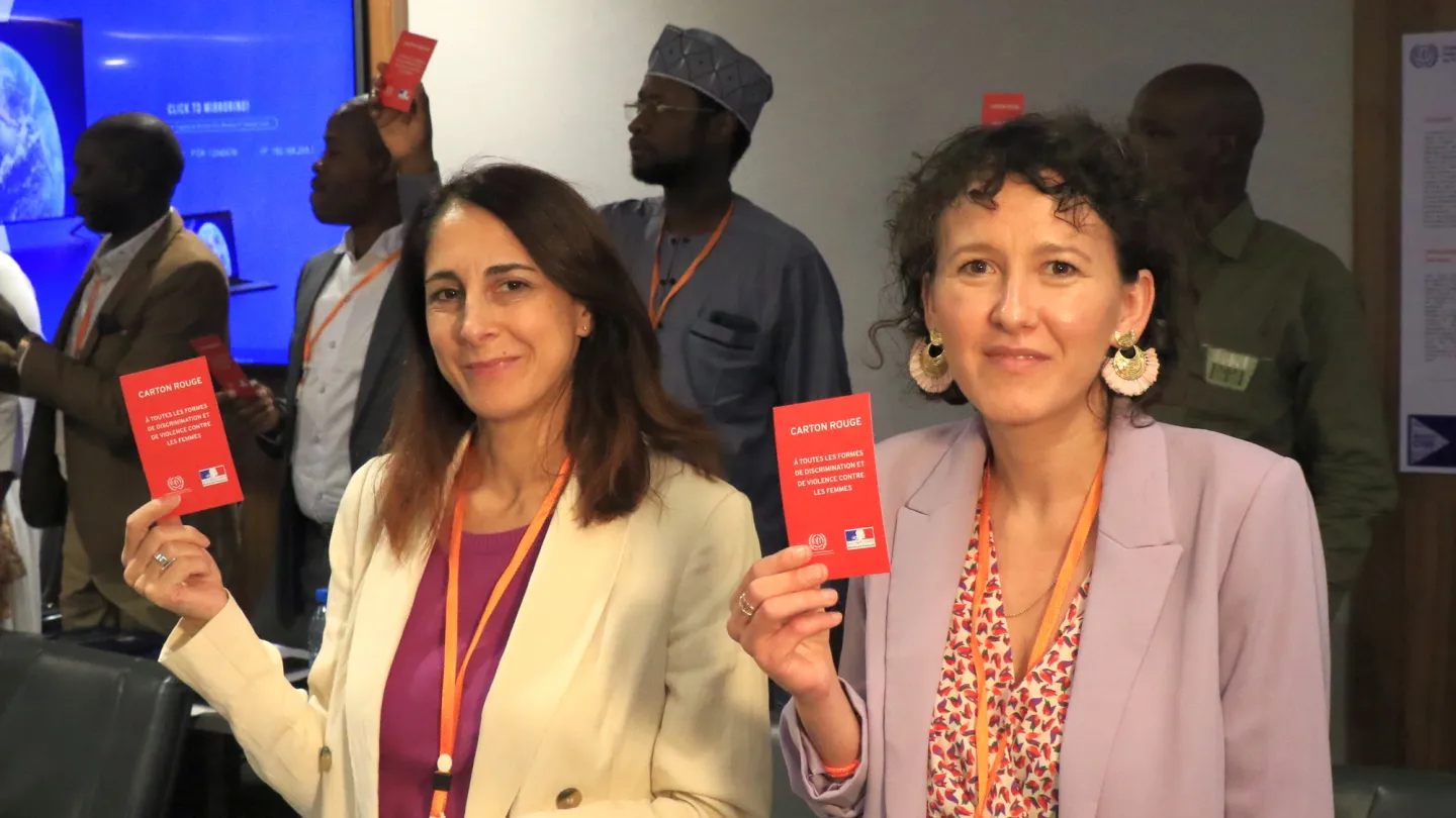 Portrait de participantes tenant un carton rouge contre la violence et du harcèlement dans le monde du travail.