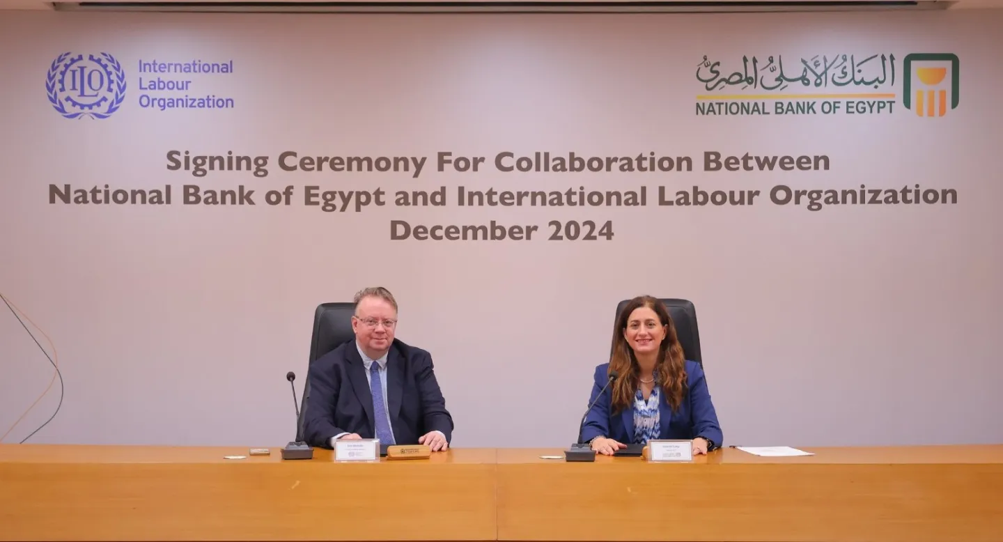 Two people seated at a table during a signing ceremony for collaboration between the National Bank of Egypt and the International Labour Organization, December 2024.