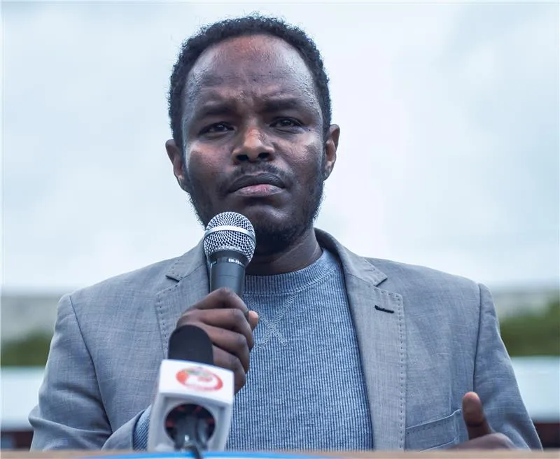 A government official speaking infront of visitors in a farm filed