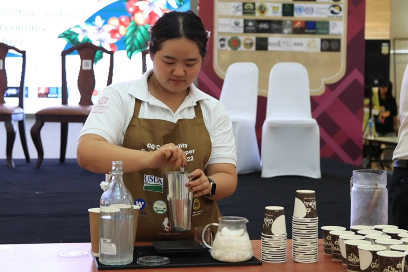 A women wearing an apron makes coffee.
