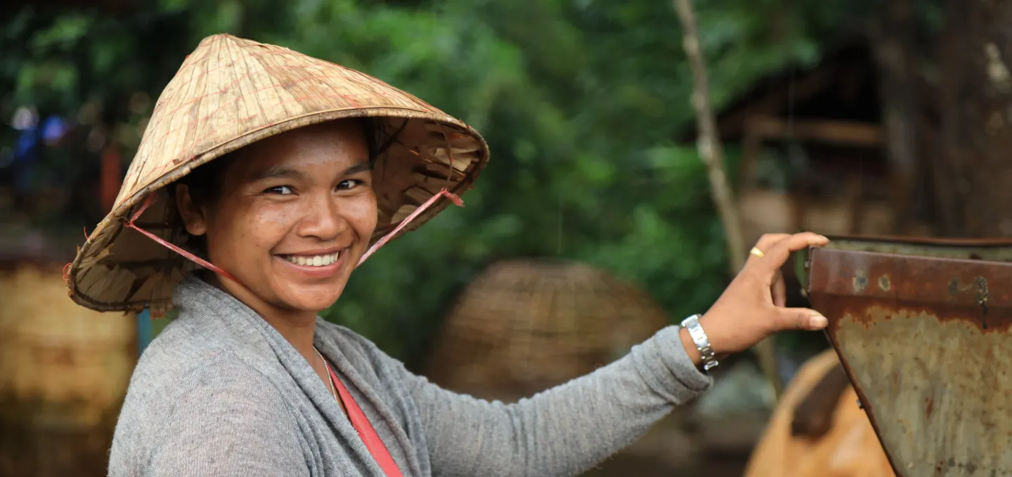A woman, wearing a straw hat, smiled.