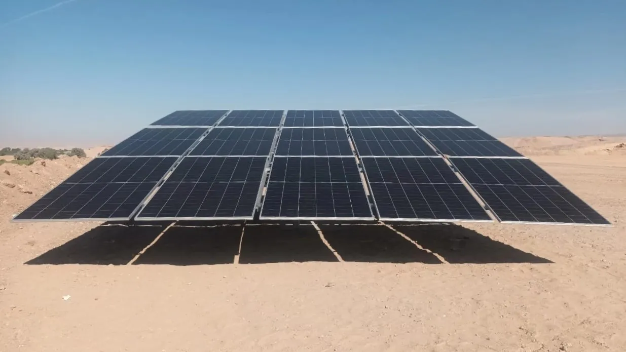 Solar panels installed on a hillside in a desert, harnessing renewable energy under a clear blue sky.