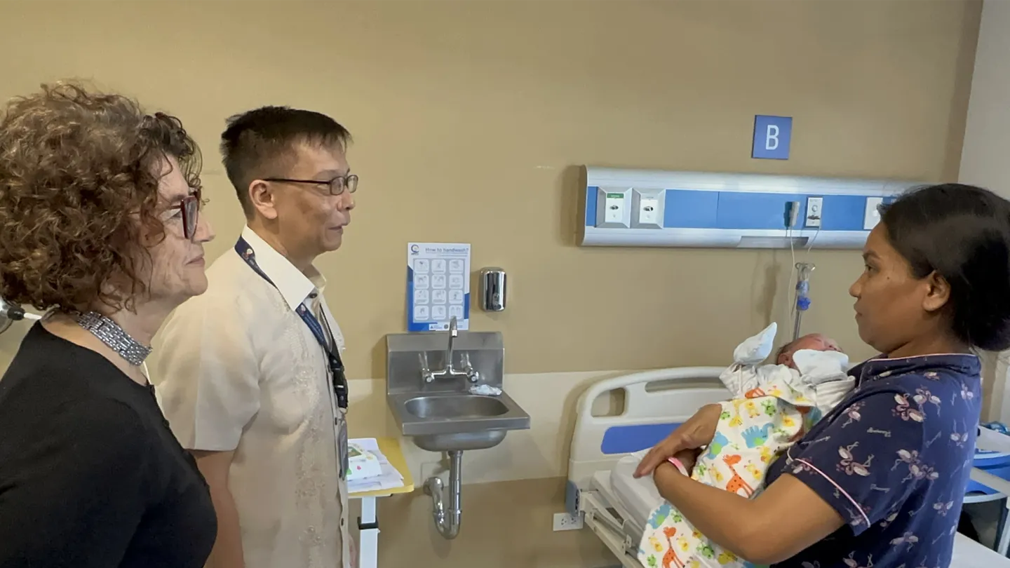 a mother carrying a newborn baby in a hospital and speaks with the ILO and DWM during their visit