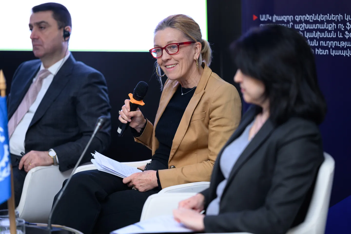 a member of the panel discussion sit smiling with a mic in hand during the high-level discussion on public works programmes (PWP) on 5 February 2025 in Armenia
