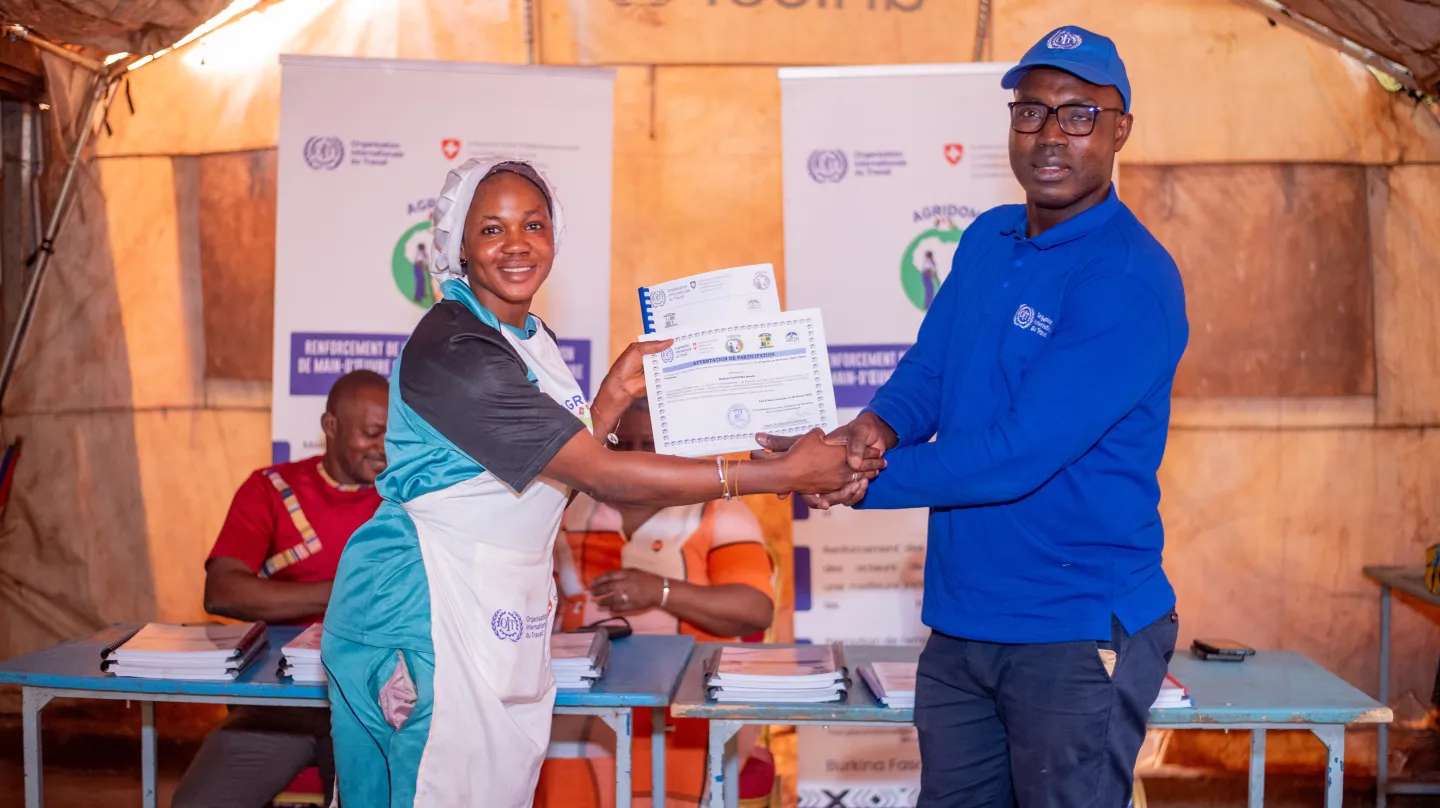 Traoré Alassane, Coordonnateur du projet AGRIDOM, remettant à Rosalie Yougouma, travailleuse domestique ayant pris part à la formation, son certificat de participation
