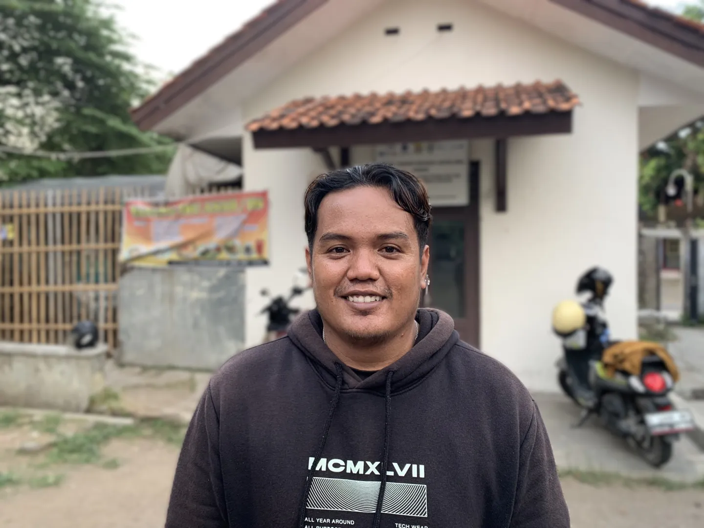 A man stands in front of a newly built house. 