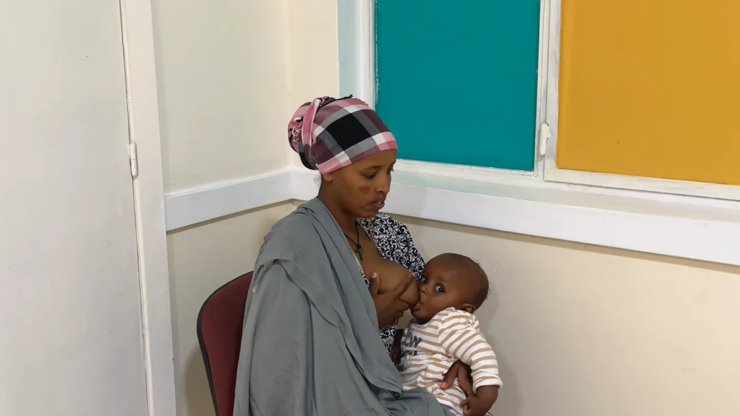 Woinshet, a garment factory worker, breastfeeding her baby in a designated space at her workplace, highlighting the importance of maternity support for working mothers.