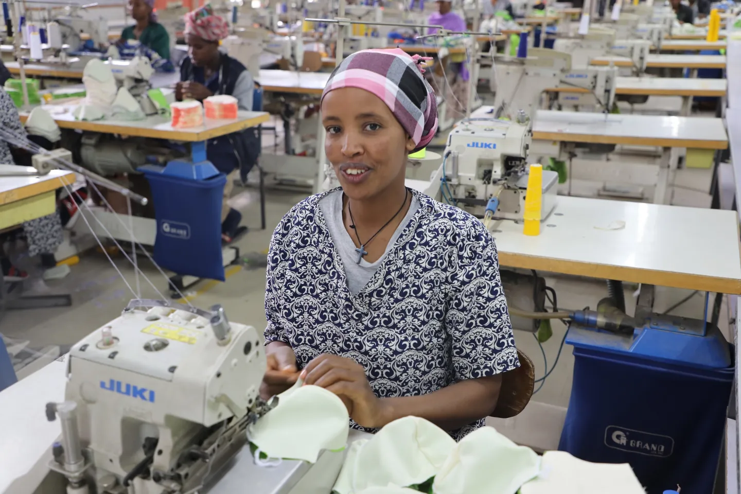 Woinshet, a worker at Yirgalem Addis garment factory, sewing fabric at her workstation, highlighting women's employment in the textile industry