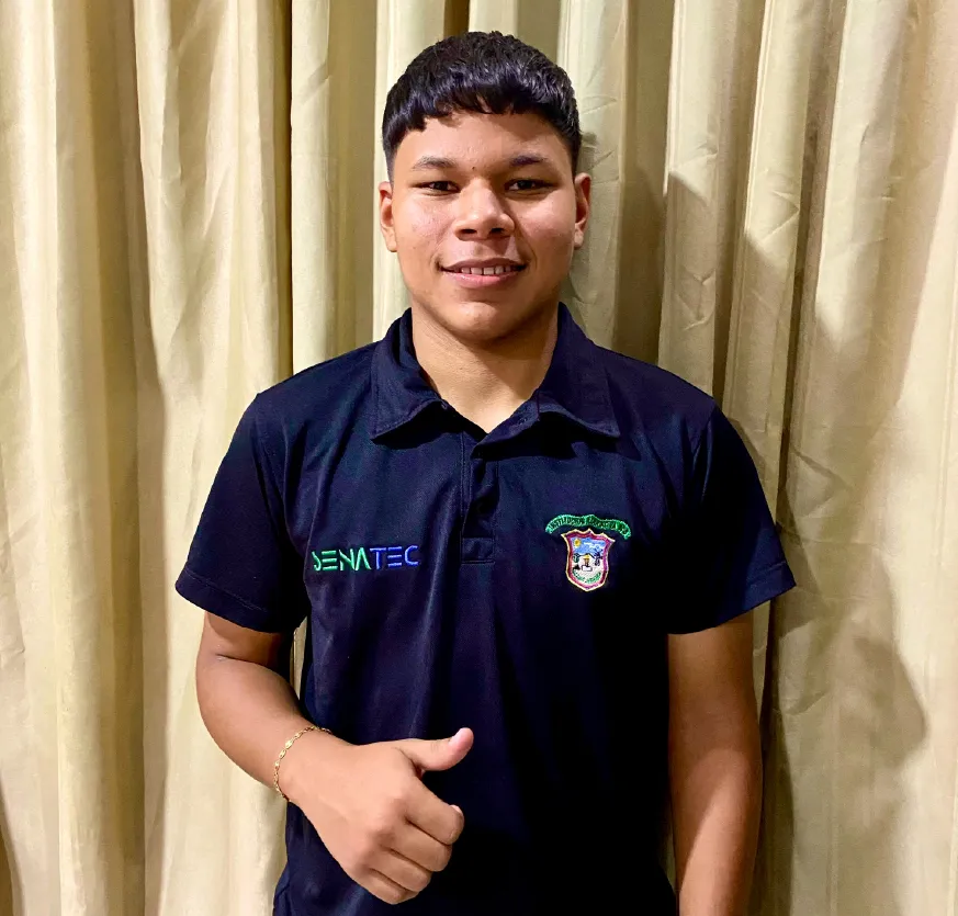 Smiling young man wearing a black polo shirt with SENATIC logos and an institutional crest, giving a thumbs-up gesture.
