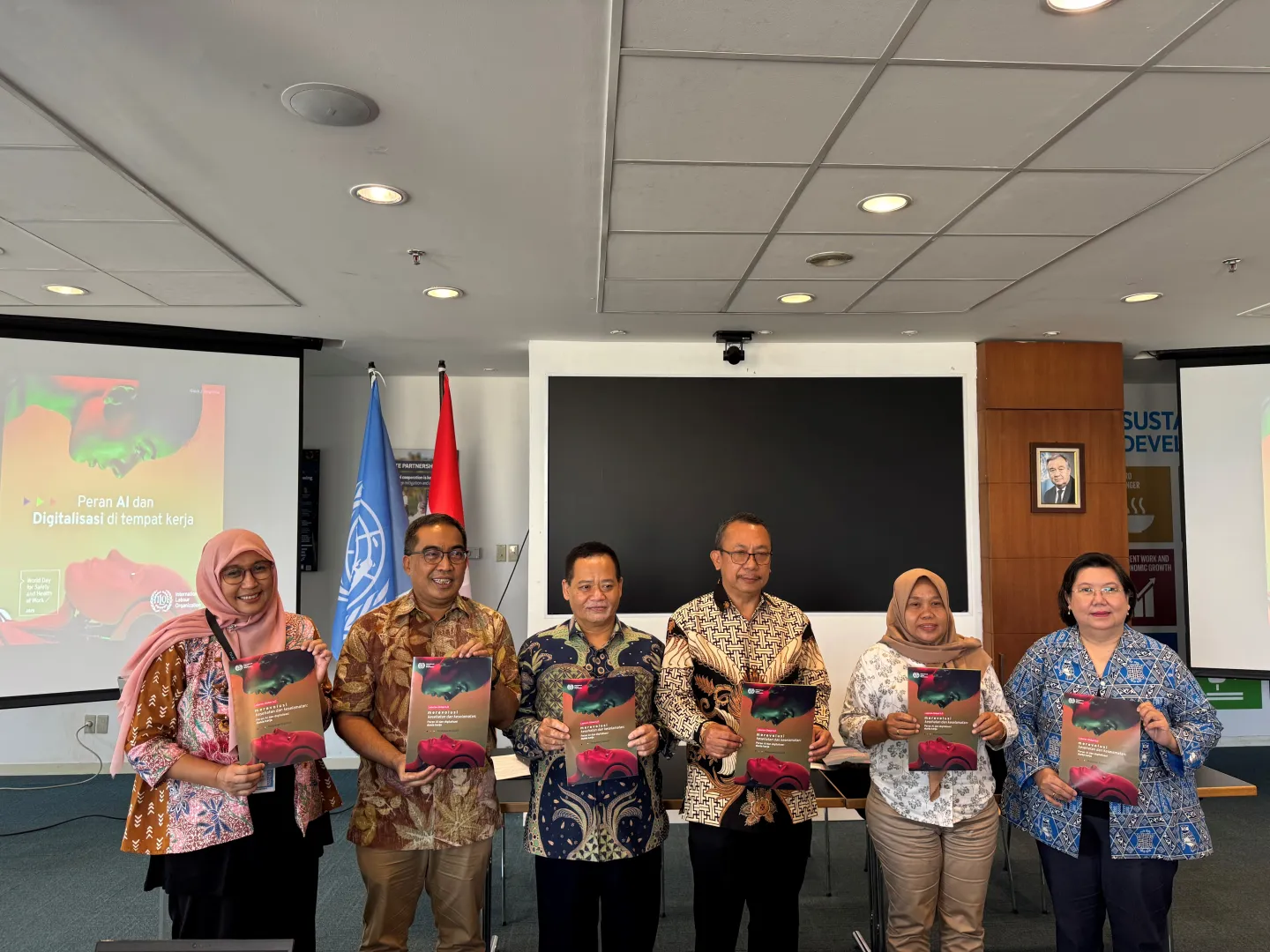 Six people standing holding a publication