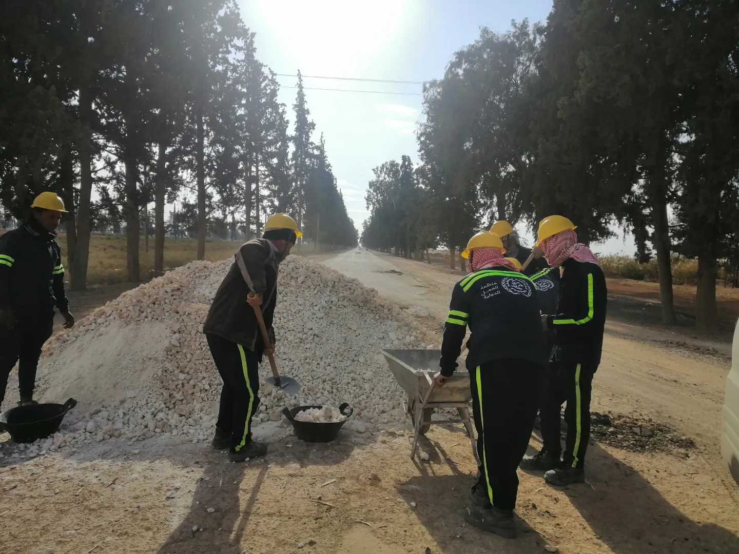 Five men mixing gravel to rehabilitate roads in rural Aleppo, Syria