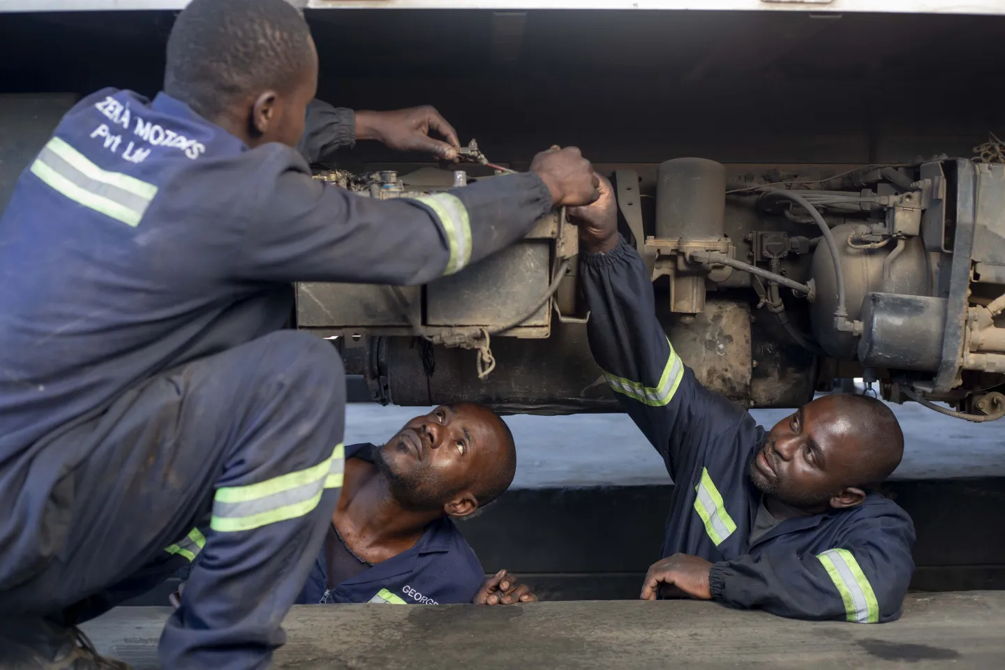 Three men repairing a car