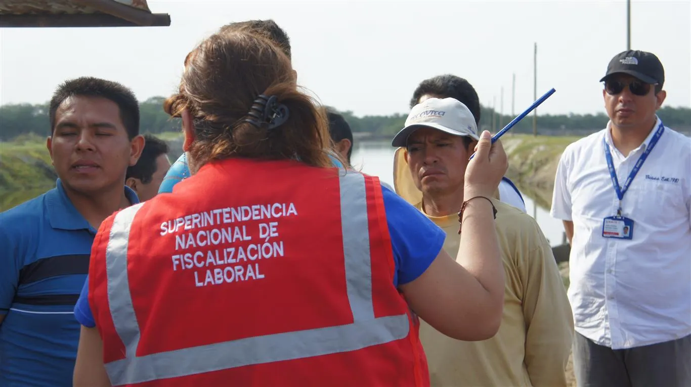 A woman labour inspector from Peru is seen from the back talking to a group of workers