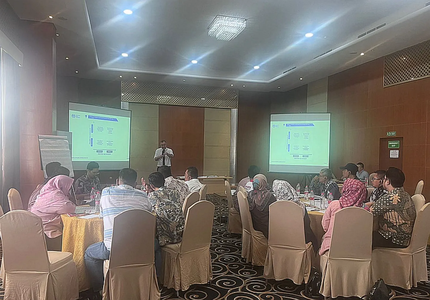 A meeting with participants sitting and one person standing on the front