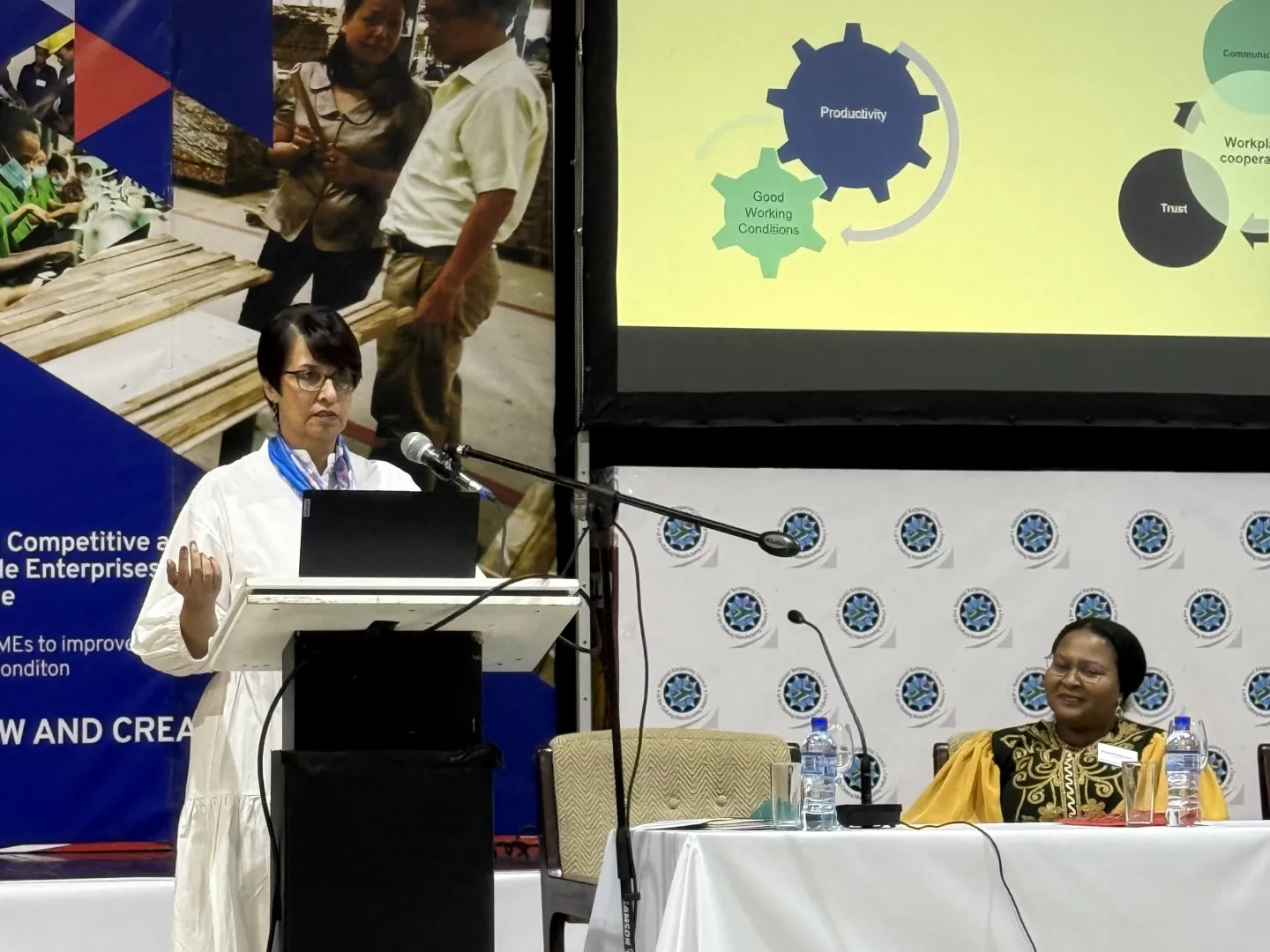 A female speaker speaks on stage at the workshop