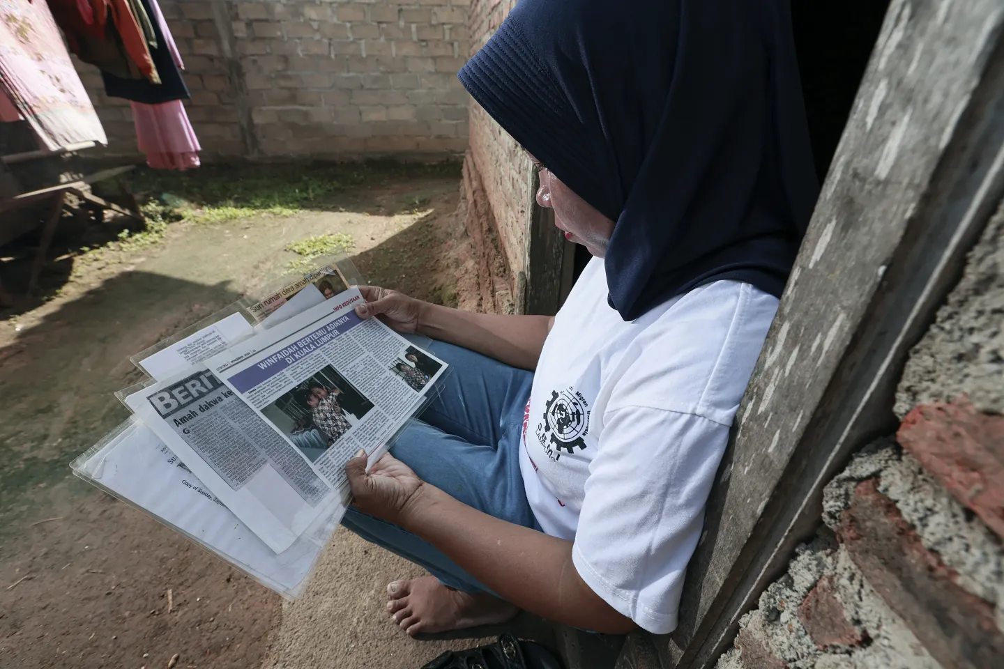 A woman is seating, reading press articles about her won story