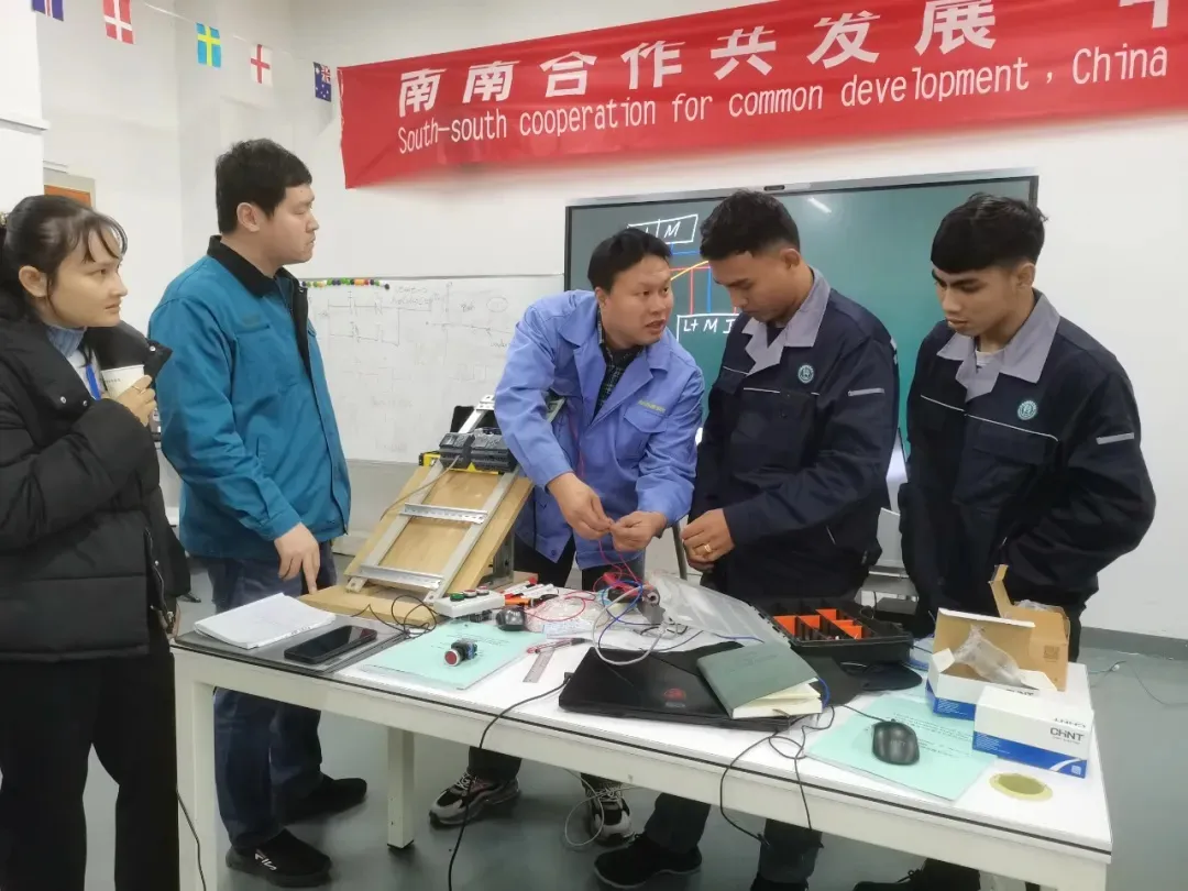 A group of five individuals gathered around a table filled with various electronic devices.