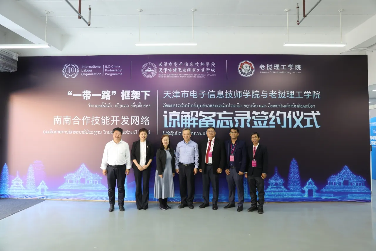 Delegates group photo in front of a large sign. 