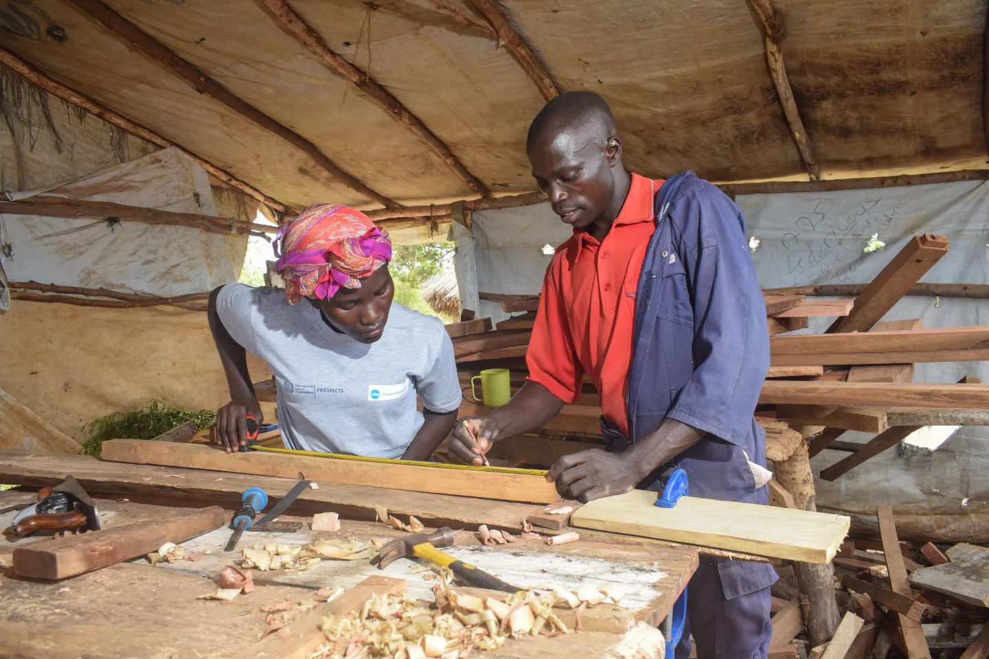 man trainer teaching a woman student wood working skills