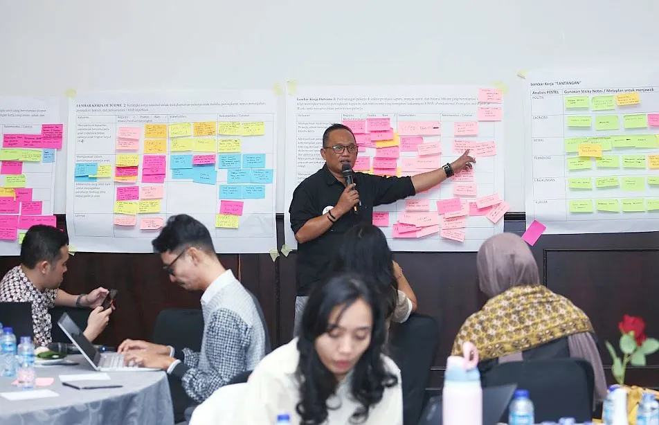 A man standing pointing to the presentation