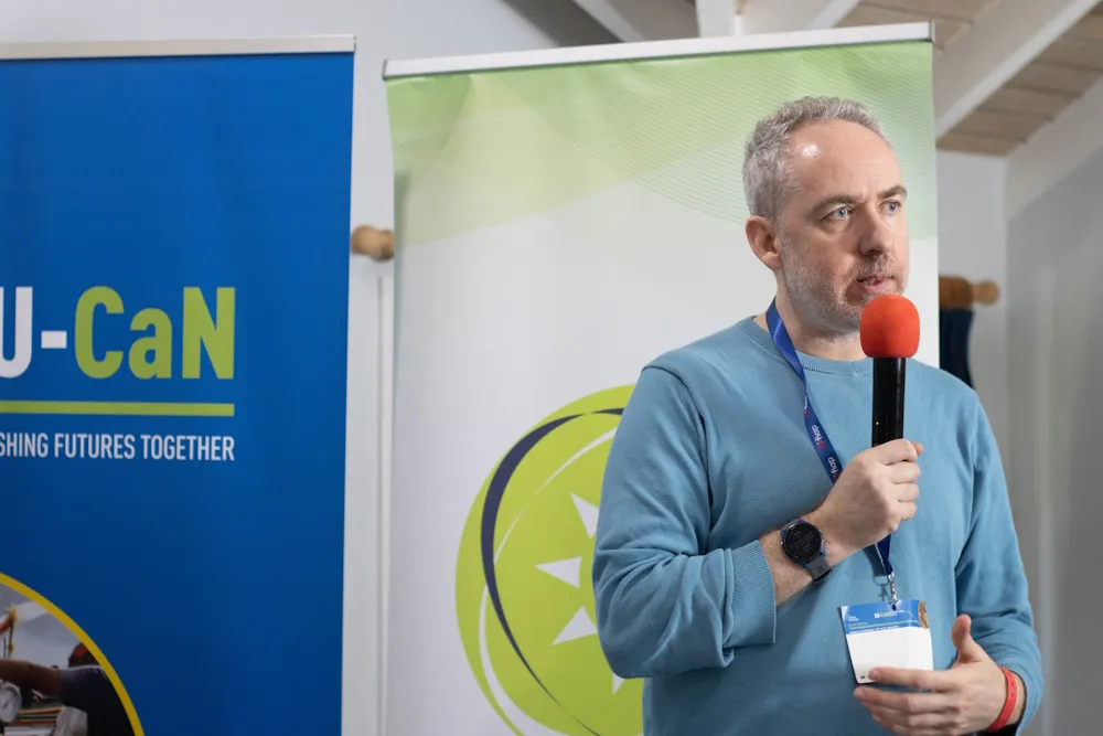 Ian Orton, ILO Specialist in Social Protection and Occupational Safety and Health standing at a podium, holding a microphone and speaking 