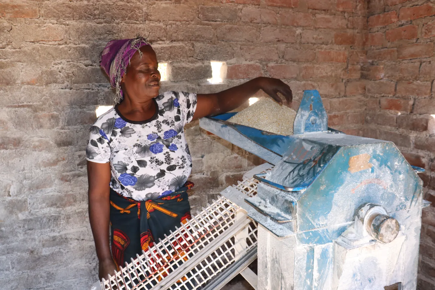 Gertrude Phiri operating a solar-powered hammer mill from her home.