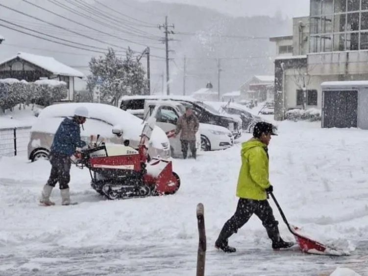 過疎化が進む山間地域で雪かきをする人々