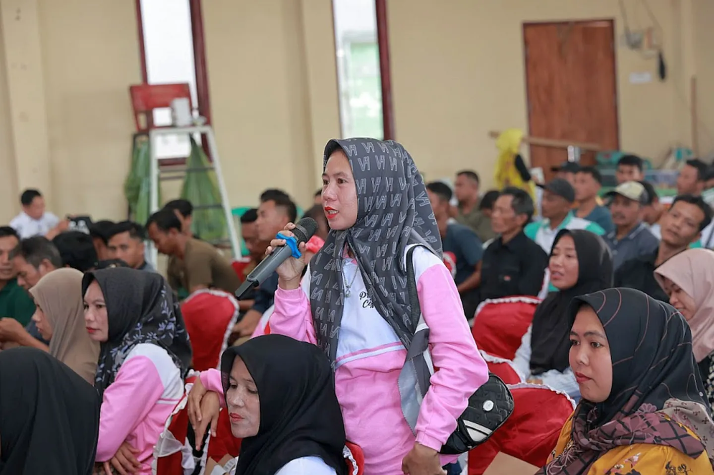 A woman standing among people sitting in the meeting